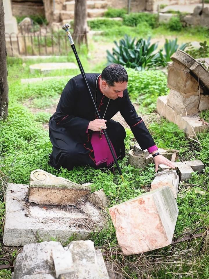 Anglican bishop looking at destroyed cemetery crosses