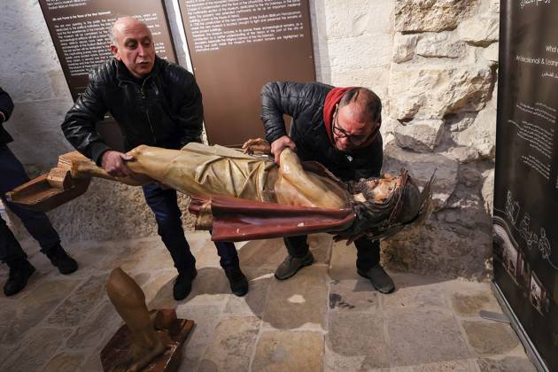 February 2, 2023, Jerusalem, Israel: Two men carefully handle an antiqua wooden statue of Jesus Christ that was pulled d