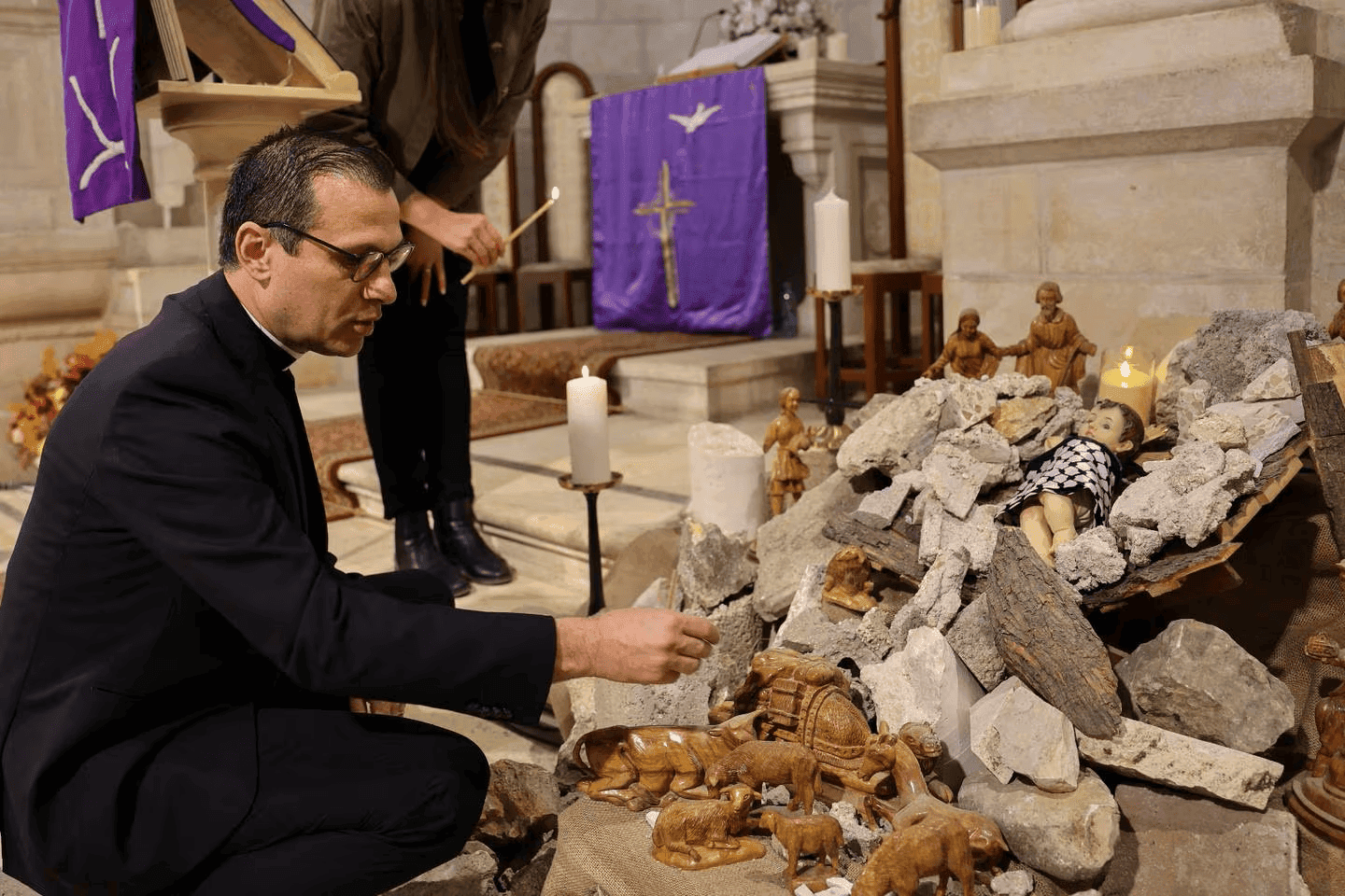 القسيس منذر اسحق في كنيسة بيت لحم اللوثرية والطفل يسوع بين الدمار Rev Isaac looking at the baby Jesus under the rubble