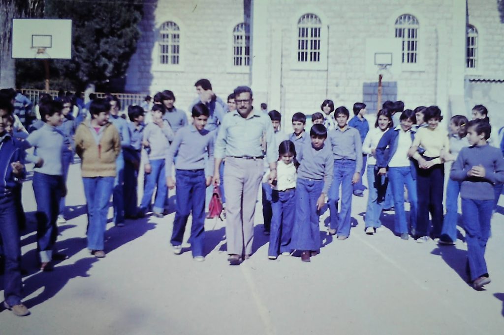 To the right of his father and with his sister Samar and brother Bader in the Baptist School